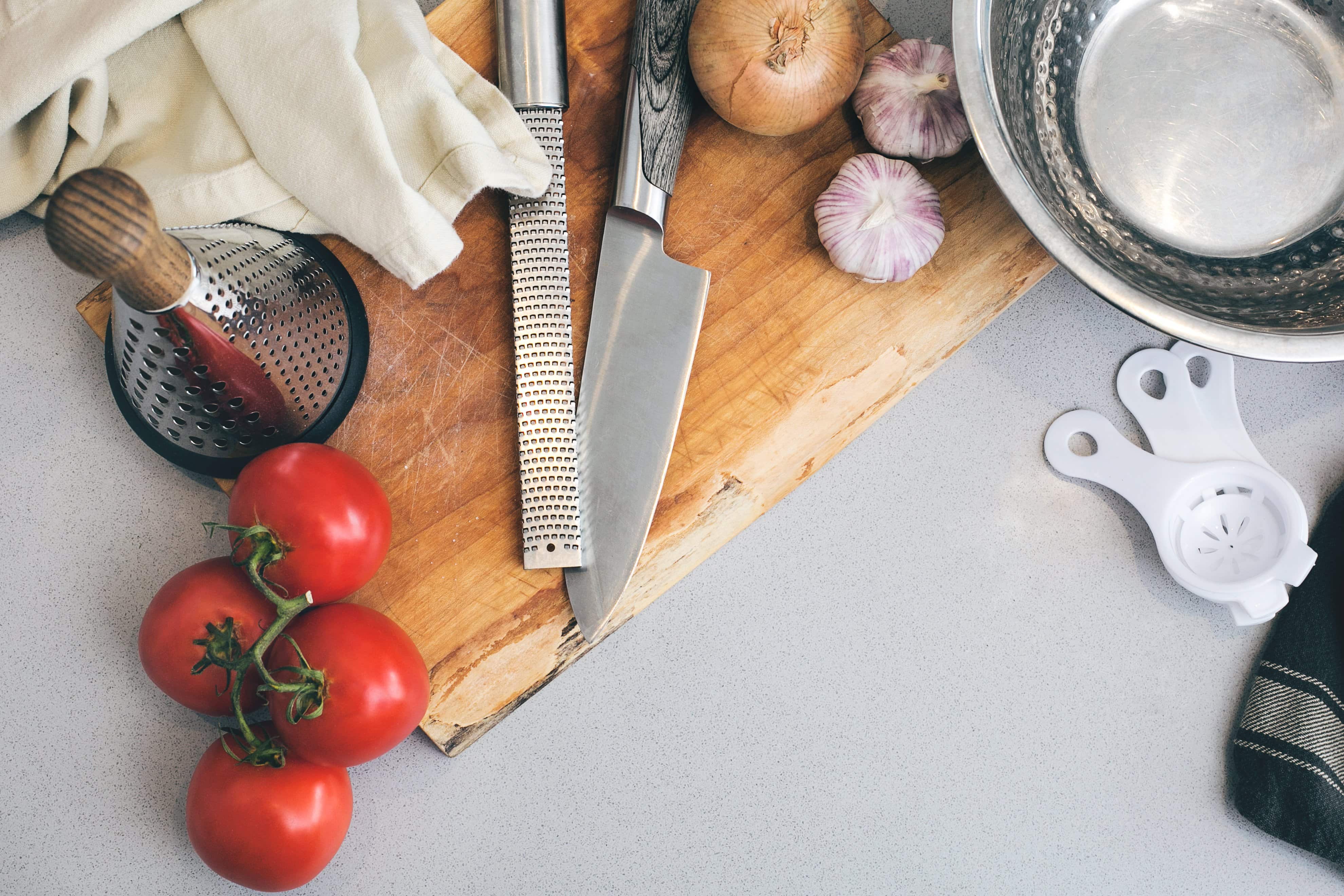 Kitchen tools sitting on wooden cutting board.