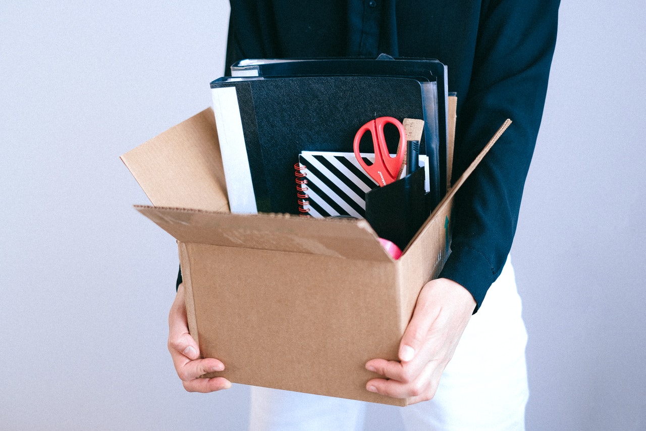 A woman holding a cardboard box filled with office supplies representing changes in termination clause enforceability